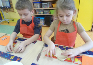 Dwójka dzieci formuje z ciasta placek w kształcie koła.